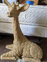 Side angle view of large sitting giraffe statue showing texture and shape