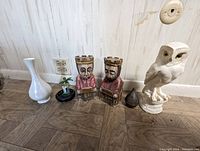 View of all items in the lot showing two wooden king bookends, small Mickey collectible, dark incense burner, white ceramic vase, and white snowy owl statue in background.
