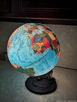 Photo of a vintage illuminated globe with a black base and power cord, showing a world map in vibrant colors.