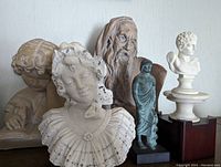 Group photo showing six statuettes including busts and full-figure statues with various classical and historical representations.