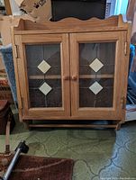 Front view of the wood wall mount cabinet with closed glass doors showing decorative diamond accents