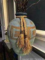 Close-up of the ceramic pot showing hand painted gold accents and braided tassel detail