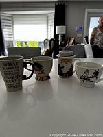 Four Christmas-themed mugs displayed on a kitchen counter with natural lighting.
