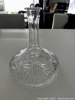 Clear glass decanter viewed from above and to side showing detailed starburst and fan patterns on wide base and narrow neck.