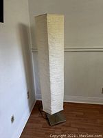 Full view of the tall Ikea floor lamp showing the rectangular white textured paper shade and metal base.