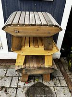 Stacked view of three wooden Muskoka style footrests showing slatted tops and legs with visible signs of outdoor wear.