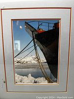 Close-up of original photograph depicting boat bow and snowy background, showing double matting and clear image detail.