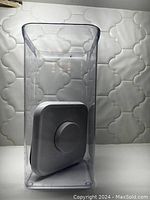 Photo showing the clear rectangular plastic container from the side with the white lid placed inside it.