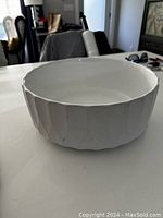Side angle showing textured ridged exterior and scalloped rim of the white ceramic bowl.