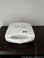 Closed white electric sandwich presser with Chefman branding and indicator lights on top