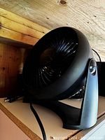 Small black table fan showing front grill, tilt stand and power cord.