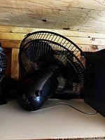 Side and front view of one small black electric fan showing circular protective metal grill, three blades, and power cord.