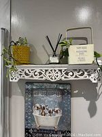 Shelf with two potted house plants on top and framed artwork below.