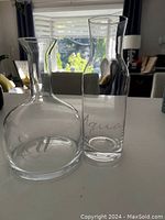 Two clear glass decanters displayed side by side on a white surface in natural light, one shorter and rounder labeled 'red', the other taller and slimmer labeled 'aqua'.