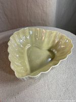 Porcelain heart-shaped dish with scalloped edges in cream color on fabric surface