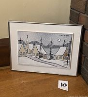 Front view of framed ceramic plaque showing village houses, church, trees, mountains, and moon with signature in top right.