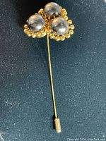 Front view of Dior vintage pin showing three large silver-tone spheres surrounded by gold-tone beads on a dark background.