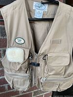 Front view of tan vintage LL Bean fisherman’s vest showing multiple pockets, fleece patch, and front zipper with buckle closure.