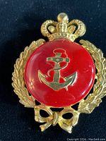 Front view of vintage custom brooch with a gold-tone anchor on red enamel background, gold-tone laurel wreath and crown embellishment.