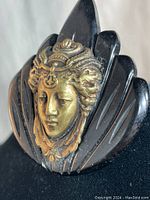 Close-up of the brass-tone Victorian figurine head detail on the black bakelite fan-shaped base.