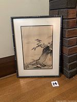 Frontal view of the vintage framed Asian watercolour painting leaning against a wall and brick pillar, showing the full composition with tree, rock, distant mountains and boat details, framed in a bamboo-style frame.