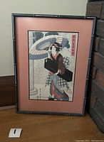 Framed Japanese woodblock print showing a full view of the item with a bamboo-style black frame and coral matting surrounding the art.