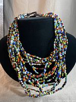 Front view of the multi-strand necklace displayed on a black bust showing vibrant multi-coloured beads.