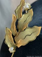 Close-up side angle view showing textured leaf details and one pearl accent on the gold filled brooch.