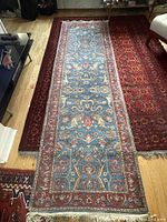 Full view of runner carpet laid over a red patterned rug