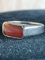 Close-up front and side views of vintage sterling silver ring with rectangular carnelian stone, showing texture and color.