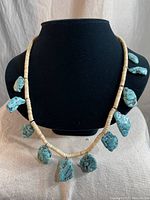 Full front view of the necklace on display bust showing large rough turquoise pendants and disk beads.