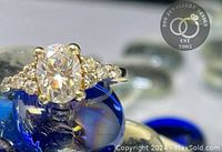 Oval-cut center stone ring with round side stones on blue display