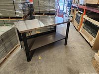 Front-left angle view showing stainless steel top, lower shelf and carbon-black legs