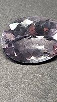 Close-up image of a natural pink amethyst oval gemstone with a fancy checkerboard cut, showing detailed facet reflections and light pink coloration.