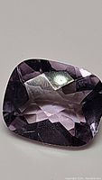 Close-up of cushion-shaped pink amethyst gemstone with fancy checkerboard faceting.