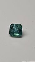 Close-up photo showing the octagon cut natural emerald with visible inclusions, highlighting color and clarity.