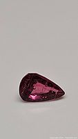 Close-up images of a single pear cut hot pink tourmaline gemstone showing its color, cut, clarity, and size.