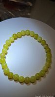 Photo of a lemon jade bead bracelet arranged in a circle on white surface showing color and size of beads.