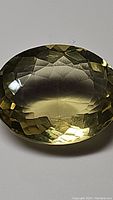 Close-up of the natural lemon citrine gemstone showing oval cut and yellow color with VVS clarity under lighting.