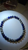 Front view of the bracelet showing alternating Lapis Lazuli and Map Jasper round beads on a white display surface under lighting.