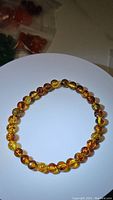 Full view of the amber bead bracelet showing the full circle of beads with natural piebald coloration, polished and strung on elastic.