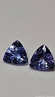 Close up of two trillion cut Tanzanite gemstones side by side highlighting color and cut.