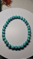 Turquoise bead bracelet arranged in circle showing bead color and pattern on white background.