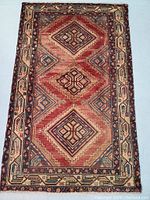 Full view of the Persian wool rug showing triple medallion pattern and geometric border.