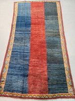 Full view of Persian Gabbeh rug showing color blocks and patterned border.
