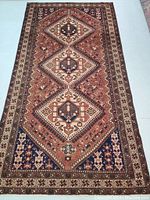 Full view of Persian hand knotted wool rug with geometric diamond medallions and floral patterns in subdued colors.