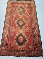Full view of Persian Lori hand knotted wool rug showing geometric tribal design in subdued red, black, and tan colors.