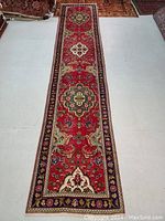 Full view of red Persian Tabriz runner rug laid out on floor
