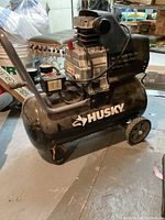 Side view of Husky air compressor showing brand name and black tank.