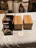 Three boxes on a table, one opened showing the boxed Pencil Buddies Artist Sketching Pencils sets, 36 packs total in lot.